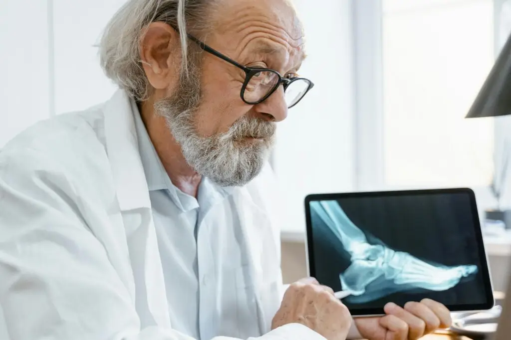 About Elderly doctor in a white coat discussing X-ray results on a tablet during a video consultation.